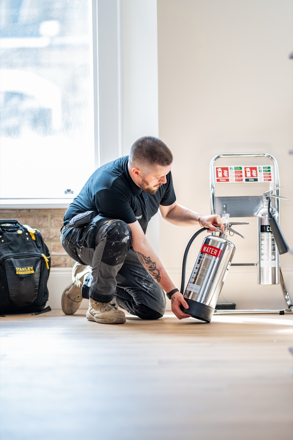 A Reeve engineer checking a fire extinguisher during a compliance visit